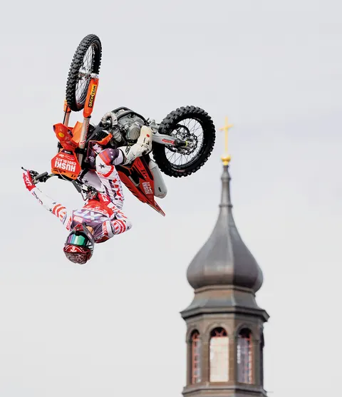 FMX-förare gör ett trick högt i luften bredvid ett kyrktorn