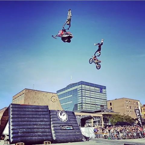 Två FMX-förare i luften över en stadskärna