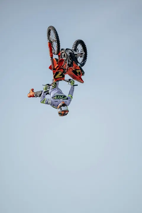 Frog FMX-förare gör ett trick högt upp mot en blå himmel